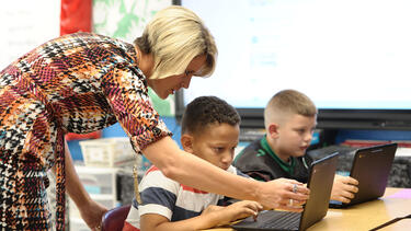 A teacher with two boys, one Black and one White