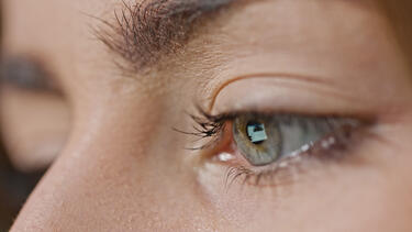 A closeup of a women's eye with a computer screen reflected in it