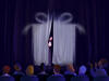 An illustration of a woman peaking through curtains in front of a gift box